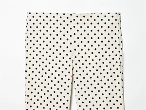 Gedetailleerde close-up van een witte Capri-broek met zwarte stippen en zijrits