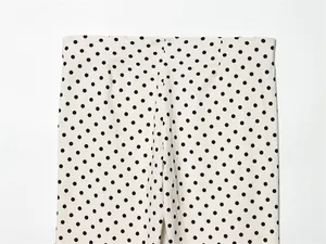 Detailopname van een witte Capri-broek met klassieke zwarte stippen en een platte taille.