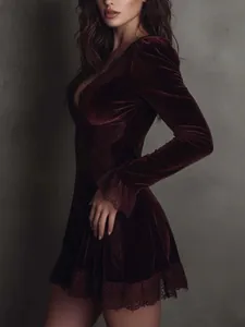 Detalle de elegante vestido de terciopelo granate con encaje en mangas y dobladillo.