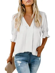 Detailed macro view of the V-neckline and pleated puff short sleeves on a white loose blouse