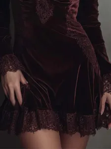 Primer plano de vestido de terciopelo burdeos con detalle de encaje en dobladillo y puños