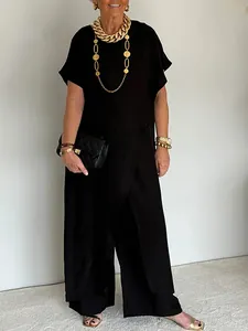 Elegante completo nero con top asimmetrico e pantaloni a gamba larga indossato da modella