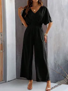 Detail of black V-neck wide-leg jumpsuit featuring elegant textured fabric and waist design
