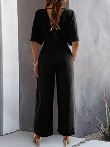 Back view of an elegant black short sleeve wide leg jumpsuit with textured fabric detail