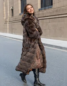 Elegant long brown hooded faux mink fur coat for women shown in a street setting