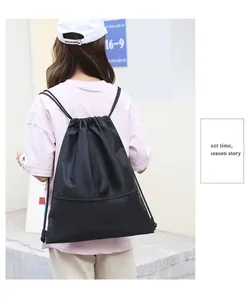 Close-up of black Oxford cloth drawstring gym bag worn by model outdoors