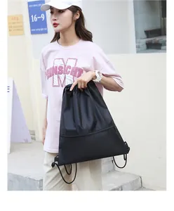 Asian model carrying a black oxford cloth drawstring gym bag with front zipper pocket