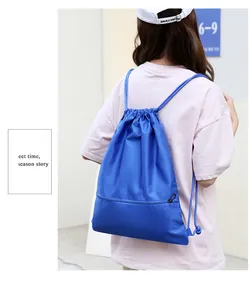 Blue oxford cloth drawstring backpack shown on a model's back in a lifestyle setting