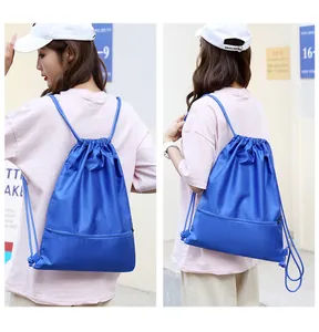 Detail view showing a blue oxford fabric drawstring gym backpack worn by a model
