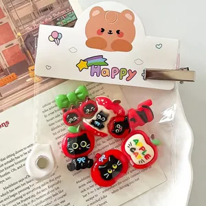 Close-up of cute DIY resin apple and cat charms for handmade hair clips and phone cases.