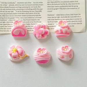 Detailed view of pink and white resin cake and flower charms for DIY crafts