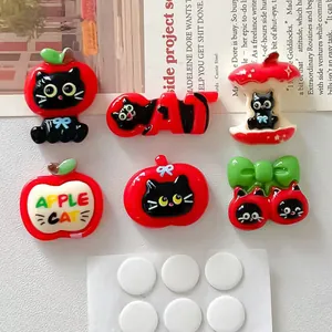 Macro view of cute black cat and red apple resin charms for DIY craft phone cases and accessories