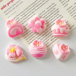 Close-up of pink resin cake and blossom charms for DIY crafts and jewelry