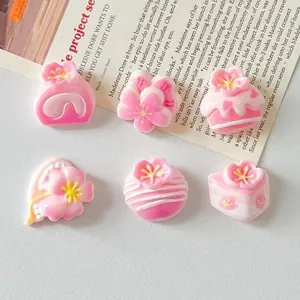 Macro view of pink and white sakura-themed resin cake charms for DIY craft accessories.