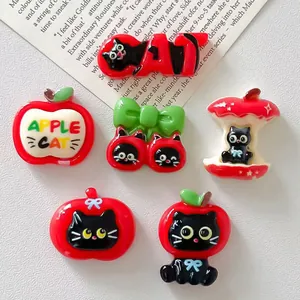 Detailed close-up of cute apple and black cat DIY resin charms for jewelry making