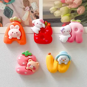Close-up view of cute cartoon resin animal and fruit letter charms for DIY projects.
