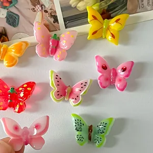 Vista detallada de dijes de mariposas de resina de colores con motivos frutales para manualidades