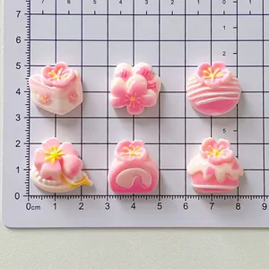 Detailed view of pink sakura cherry blossom resin charms on a metric measuring mat