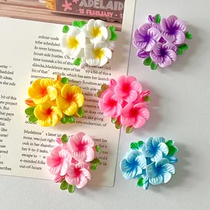Close-up of colorful glossy resin flower charms with green leaves for DIY crafts
