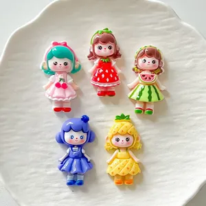 Dettaglio di cinque ciondoli in resina a tema ragazze frutta su un piatto bianco