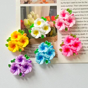Macro view of assorted colorful glossy resin flower patches with green leaves for DIY crafts