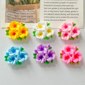 Macro view of colorful resin flower clusters with green leaves for DIY hair accessories and crafts