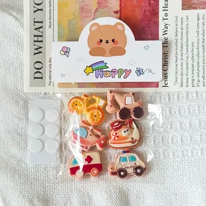 Macro view of 6-piece cartoon vehicle resin DIY charms set with adhesive dots in cute packaging