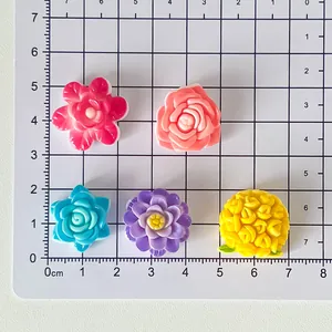Colorful resin flower charms on a centimeter grid ruler for DIY craft sizing reference