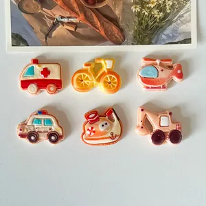 Macro view of cute cartoon vehicle resin charms like excavator and police car for DIY crafts.