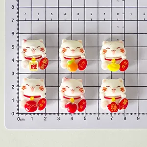 Six mini Maneki-neko lucky cat resin charms shown on a centimeter measurement scale