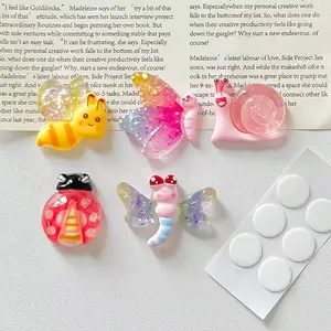 Close-up of colorful cartoon resin insect charms with adhesive dots for DIY crafts
