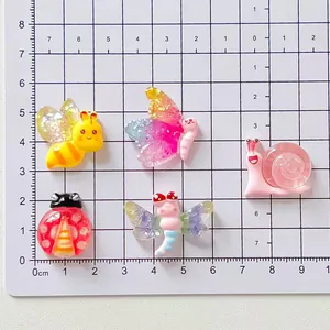 Detailed view of DIY cartoon resin insect charms on a scale mat for size reference