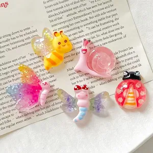 Detailed macro view of luminous resin bee and ladybug charms on a magazine background.