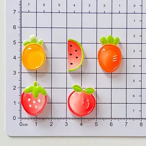 Cinco dijes de resina de frutas translúcidas sobre una rejilla de medición para escala