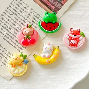 Close-up of cute resin animal charms including frog on watermelon and cat on banana.