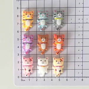 Vue détaillée de divers accessoires en résine de chat colorés sur une plaque de mesure