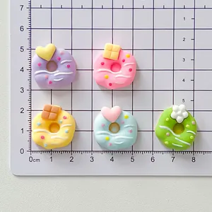 Close-up detail of colorful sweet resin donut charms on a metric measurement grid background