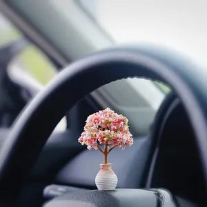 Detailed close-up of a miniature cherry blossom tree ornament on a car dashboard