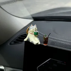 Macro view of healing cat figurine and mini iced coffee ornament on car dashboard