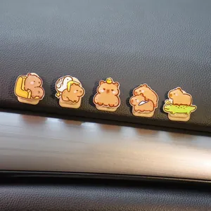 Primer plano de cinco bonitos ganchos adhesivos de capibara de dibujos en salpicadero