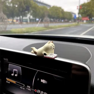 Miniature healing cat figurine car ornament reading on dashboard screen detail view