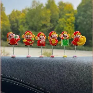 Macro detail of six cute cartoon God of Wealth figurines on car dashboard spring mounts