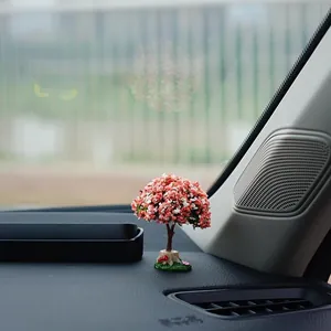 Detailed close-up view of a miniature pink artificial tree ornament on a car dashboard