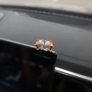 Close-up detailed view of two cute lucky cat figurines on a car center console screen.