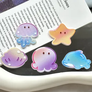 Detailansicht glitzernder Acryl-Zubehörteile mit Meeresmotiven wie Delfin und Seestern.