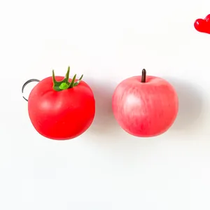 Close-up of realistic 3D simulation tomato and apple fruit fridge magnets on white