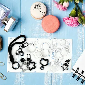 Flat lay of black and white DIY keychain charms featuring star, bow, and cat shapes