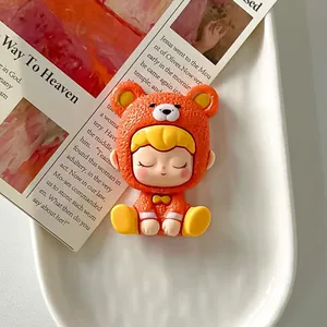 Détail en gros plan d'une figurine de fille en résine avec un costume d'ours orange