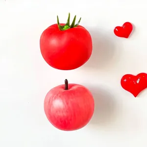 Detailed view of realistic red apple and tomato refrigerator magnets on white surface