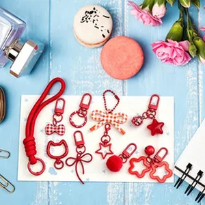 Red themed cute DIY keychain set with bowknot and star charms on blue wooden background props